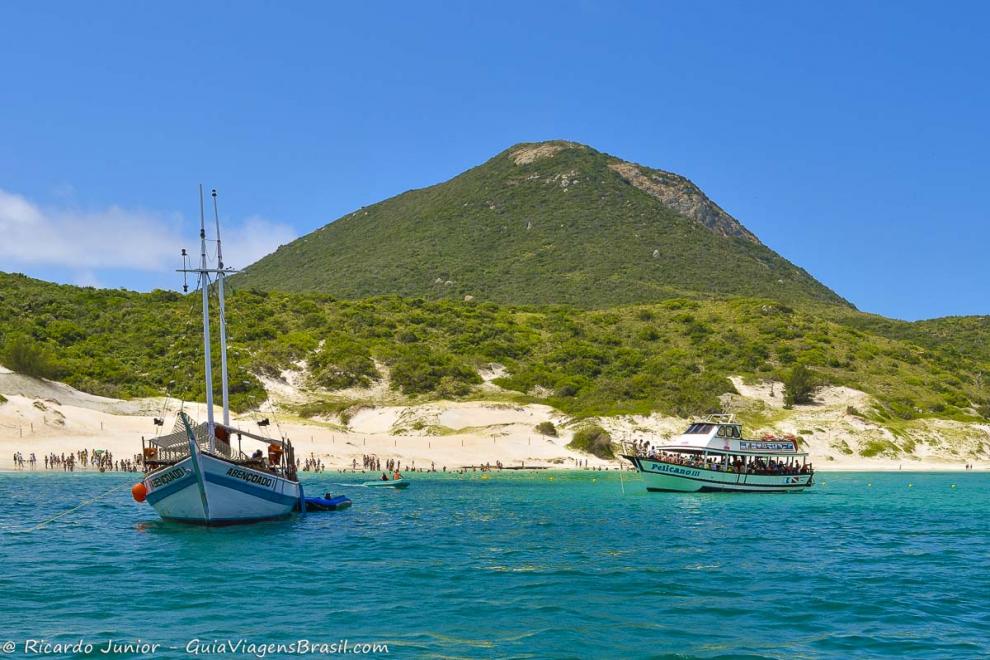 Imagem de dois barcos de passeio no mar azulada de Arraial.